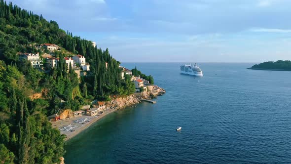 Aerial shot of a beach on the coast of Croatia with a cruise ship at sea, Europe