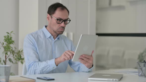 Attractive Middle Aged Man Using Tablet in Office