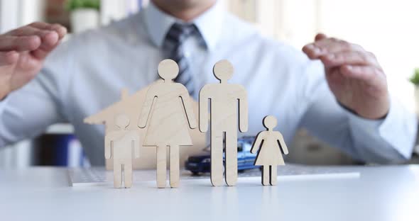 Man Making Roof with His Hands Over Wooden Figurines of Men in Family Closeup  Movie