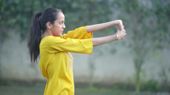 Indian woman doing hand stretch exercise and Yoga in a park