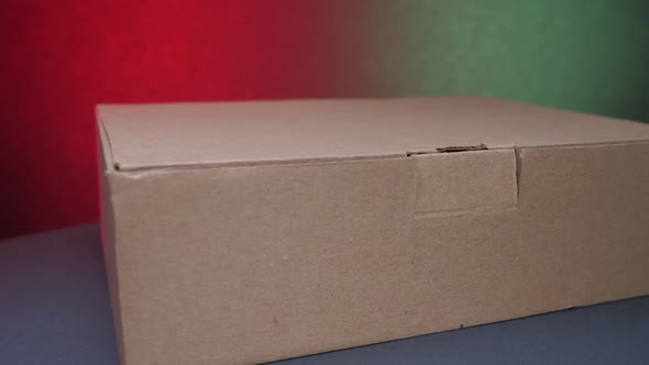 Brown Paper Box Lies on Table Against Green and Red Wall