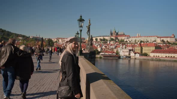 Mother And Daughter Standing On Charles Bridge Looking Out Over River