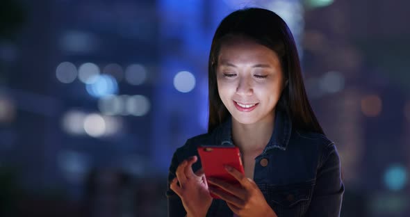 Young woman check on mobile phone in city at night