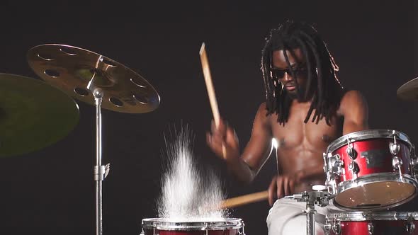 Wet Drum Set Covered with Water Drops, African Young Man Beating on Drum Set with Sticks