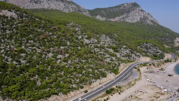 Aerial View of Road with Cars Near a Mountain and Ocean