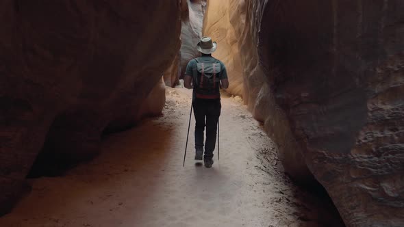 Sport Tourist Man Trekking On Dry Riverbed In Deep Slot Canyon With Orange Rocks