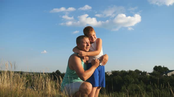 Little Red-haired Boy Hugging His Father on the Lawn. Cheerful Son Embracing His Dad with Love on
