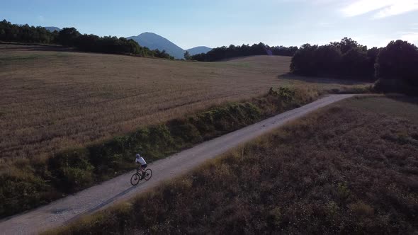 Biker riding on dust road, Marche, Italy