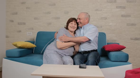 Senior Couple Sitting on Sofa and Talking About Their Happy Moments Together