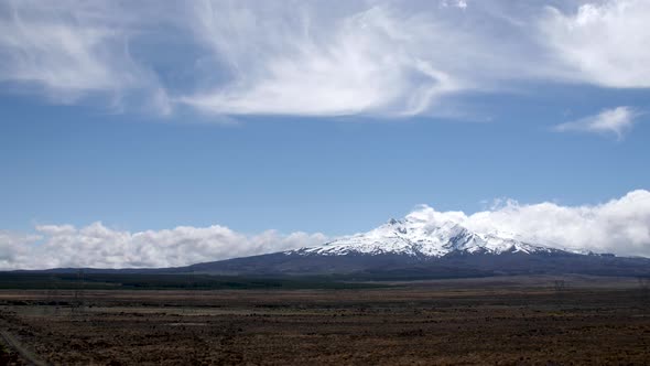 Wide establishing shot of Mount Ruapehu surrounded by beautiful clouds in New Zealand.