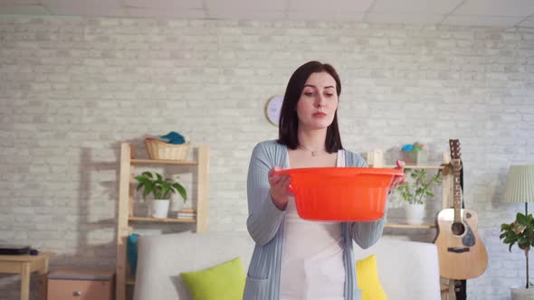 Confused Young Woman Catches of Water Drops From the Ceiling and Looks at the Camera