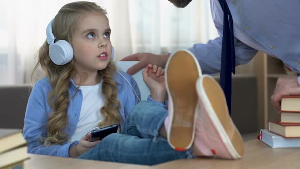 Strict Father Shouting at Daughter Listening to Music in Headphones in Room