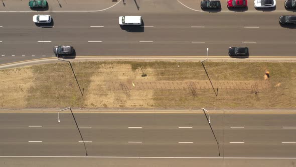A top down view directly over a highway median on a sunny day. With traffic on one side of the media