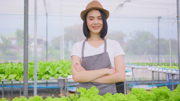 Asian female farmer owner working in vegetables hydroponic farm with happiness and looking at camera