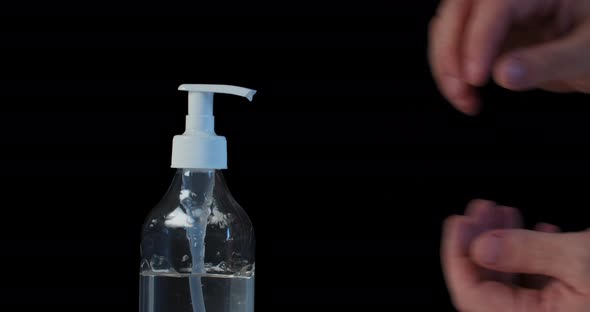 Man Push Dispenser and Liquid Soap Squeezed Out To Hand, Black Background. 