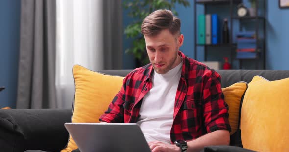 Smiling Young Man Using Laptop Sitting on Couch at Home Handsome Male Shopping or Chatting alt