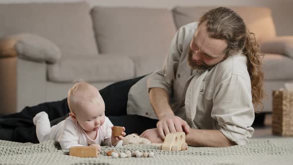 Happy Adult Parent Dad Helping Cute Infant Newborn Toddler Son Daughter Playing Toys Together on