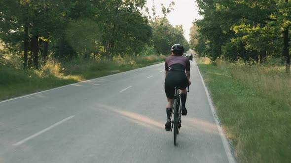 Woman cycling. Cyclist training on road bike at sunset. Cycling training at sunrise.