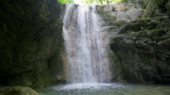 Majestic tropical jungle waterfall crashing down into cave in slow motion