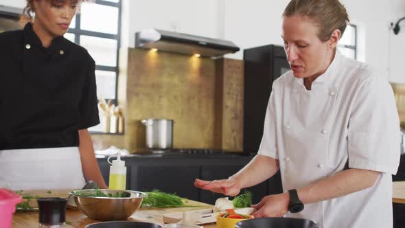 Caucasian female chef teaching diverse group wearing face masks