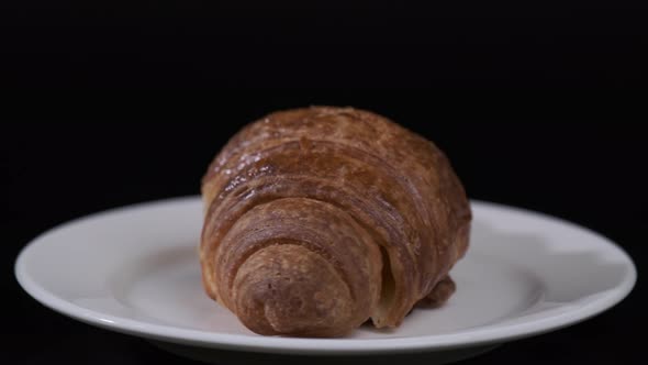 Croissant on white plate rotating in front of camera, Close-up rotates