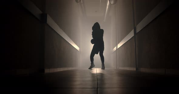 Boxer boxing with a shadow in a semi-dark corridor with a backlight behind his back, slow motion.