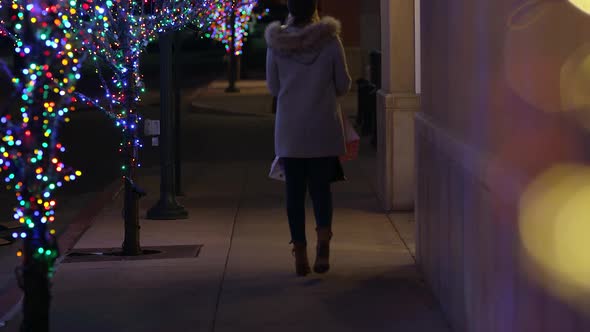 Woman walking down sidewalk with shopping bags