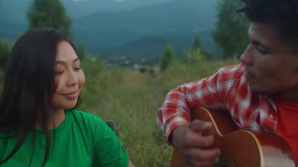 Relaxed Multiracial Couple Travelers Enjoying Leisure Playing Music on Mountain Hill