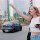 Young woman outdoor hailing taxi raising hand using smartphone - VideoHive Item for Sale