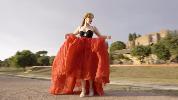 Beautiful woman dancing in a red dress, rotating pull away shot