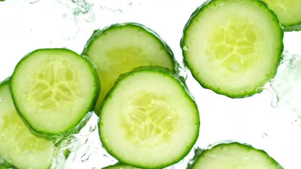 Super Slow Motion Shot of Cucumber Slices Falling Into Water on White Background at 1000Fps.