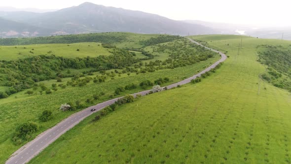 panorama of the mountain landscape. a black car is driving along the road.