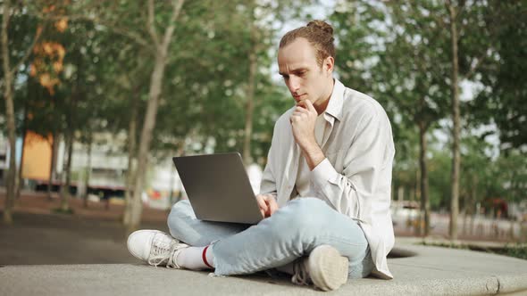 Concentrated curly-haired man working on laptop