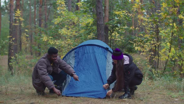 Interracial Travelers Couple Setting Up Camp Tent