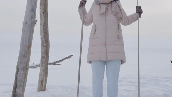 Young Woman Swinging Standing with Her Feet on a Swing in Winter Snowy Horizon