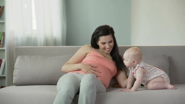 Beautiful Pregnant Woman Touching Belly Gently, Enjoying Time With Cute Baby