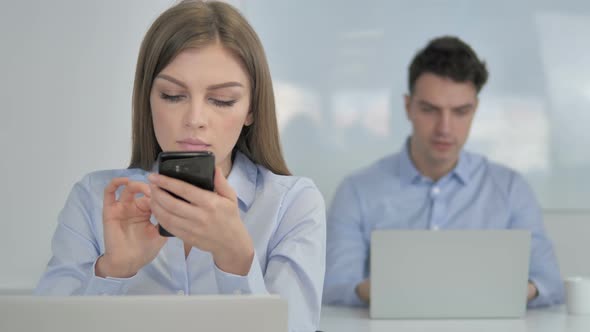 Young Businesswoman Using Smartphone at Work