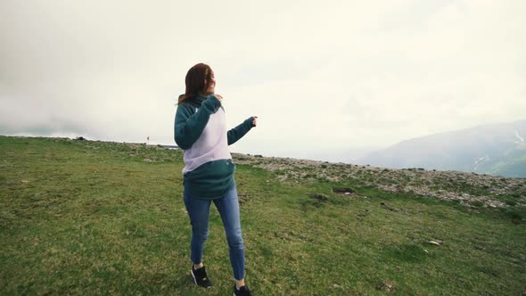 A Young Woman Hiker Running and Spinning on Top of a Mountain