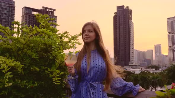 Young Beautiful Woman in Elegant Dress Hold Cocktail at Rooftop Bar Terrace