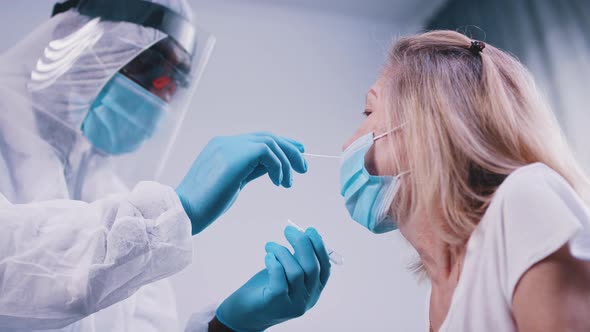 Black Doctor in Full Uniform Performing Nasal Swab Covid Tes on an Elderly Woman