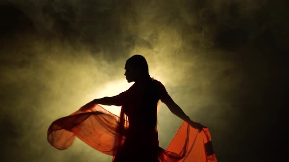 Silhouette a Young Girl Dancer in a Red Sari. Indian Folk Dance. Shot in a Dark Studio with Smoke