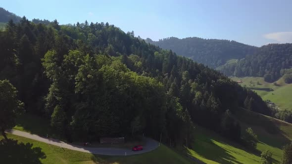 A red Ford Focus RS drives out of a forest into a beautiful open mountain scenery.