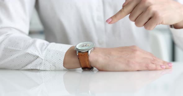 Person Points Finger at Wristwatch Closeup