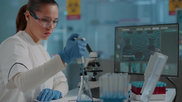 Chemist Working on Experiment with Micro Pipette and Beaker