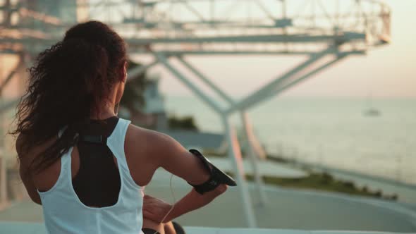 A back view of an african american woman wearing earphones doing stretching her legs