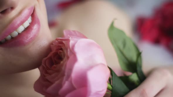 Portrait of a Sexy Woman Lying in the Bathroom with Foam and Holding a Pink Rose