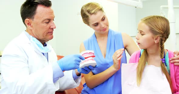 Dentist showing young patient how to brush teeth