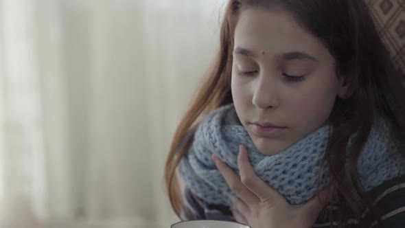 Portrait of Teenage Girl Wrapped in Warm Scarf Holding a Cup of Hot Tea in Hands