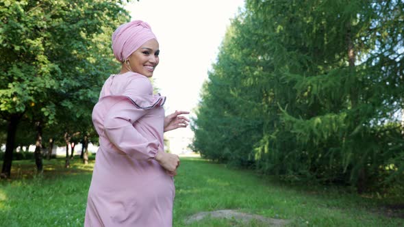 Athletic Girl in Purple Dress and Hijab Runs Along Path