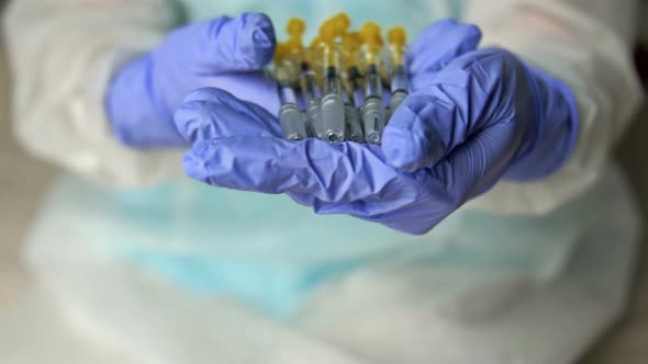 Hands of a Nurse in Protective Latex Gloves Hold Syringes Prepared for Vaccination